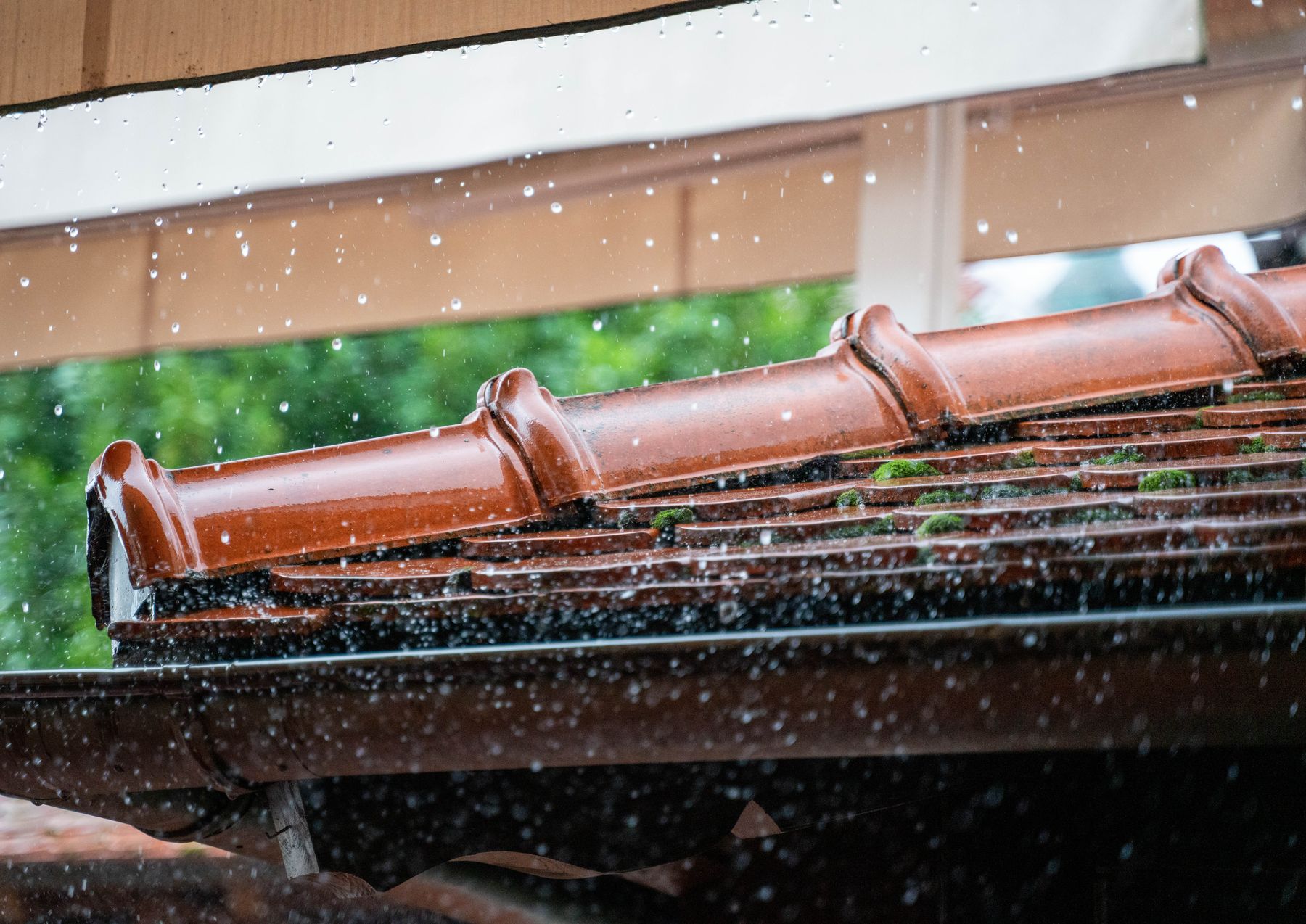 Regen auf Firstziegeln und Dachrinne